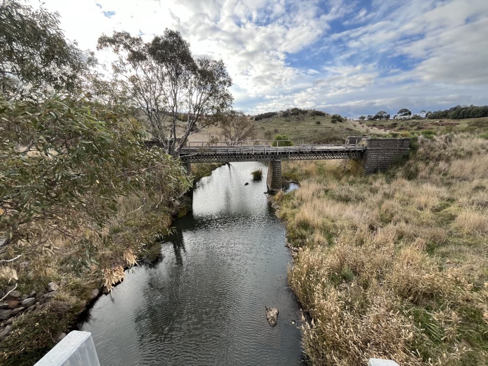 looking at Birch Creek with the sky reflected in the water and a bridge in the background  