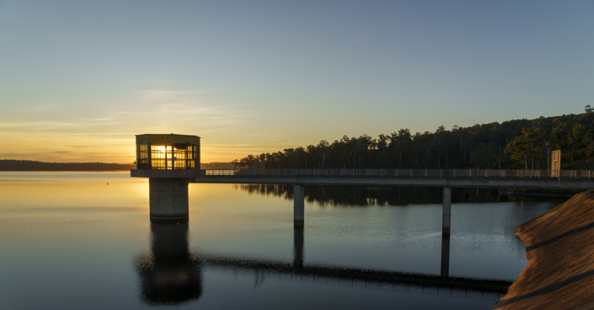 The sun sets behind Blue Rock Lake's outlet tower