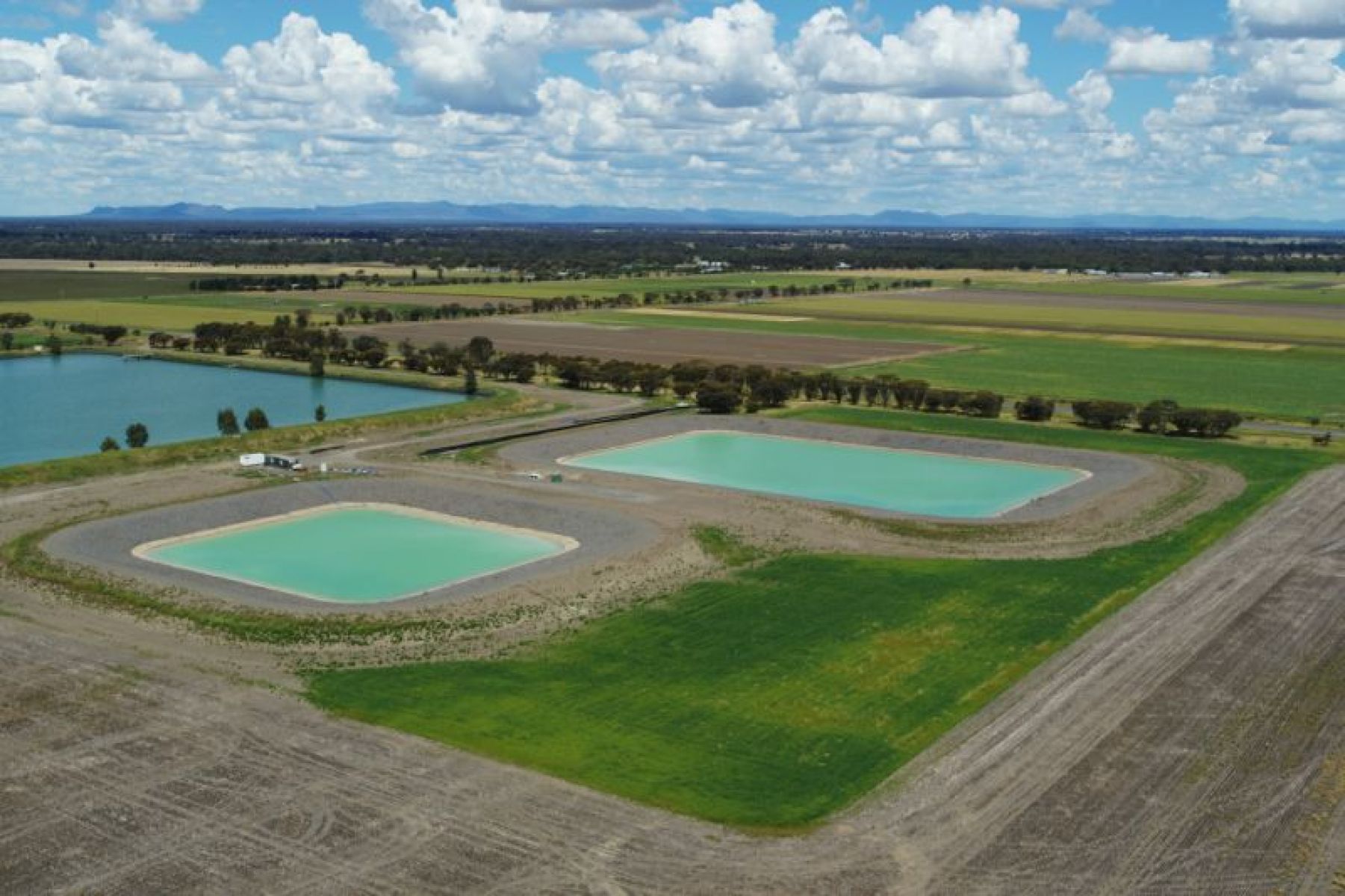 two aqua coloured dams and a blue dam at the Horsham SmartFarm, with clouds in a blue sky overhead