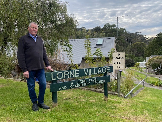 Clive Goldsworthy standing in from of the Lorne Village sign